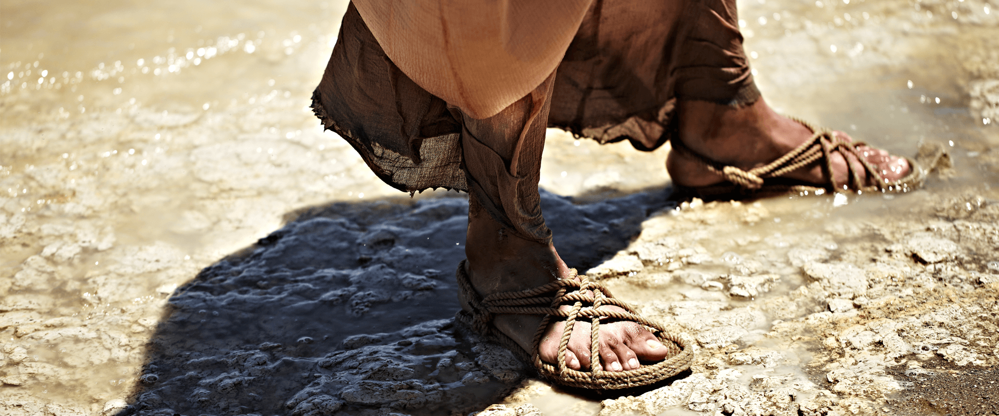 Sandaled feet on bank of river