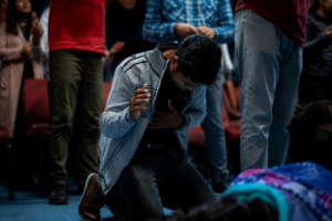 Man praying on his knees in a crowd of people